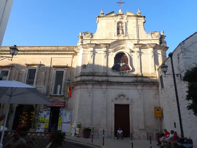 A pale stone church with a tower on a small town square
