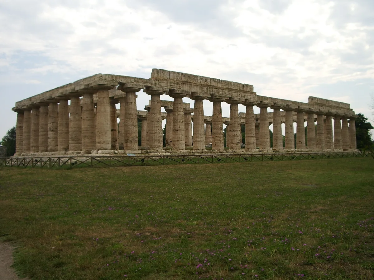 Doric Greek temple with rows of thick stone columns on a grass field