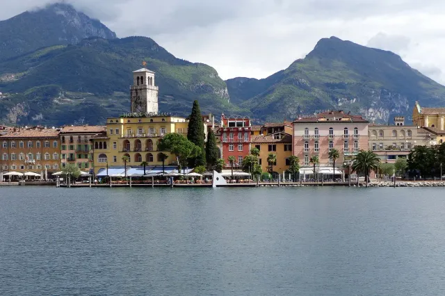 A colourful town front on a lake shore below high cliffs