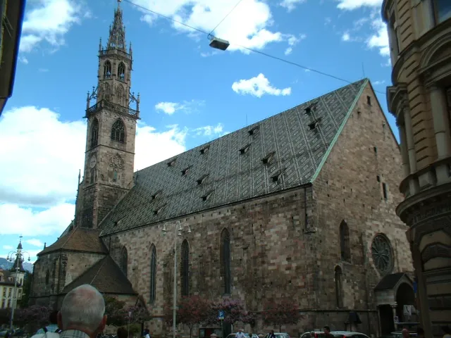A Gothic church with a patterned tiled roof and a filigree spire
