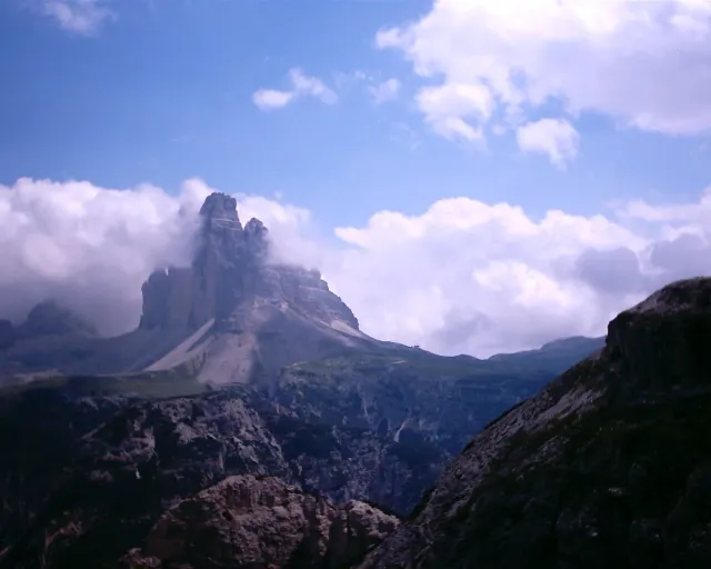 Three sheer rock summits standing above ridges and cloud