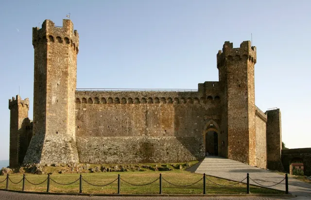 A stone fortress with battlements and towers above a lawn
