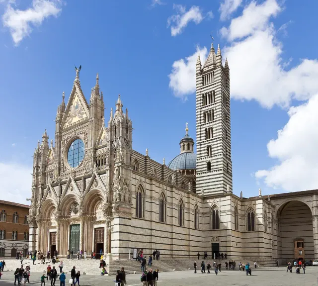 A striped black and white marble facade with statues and a banded tower