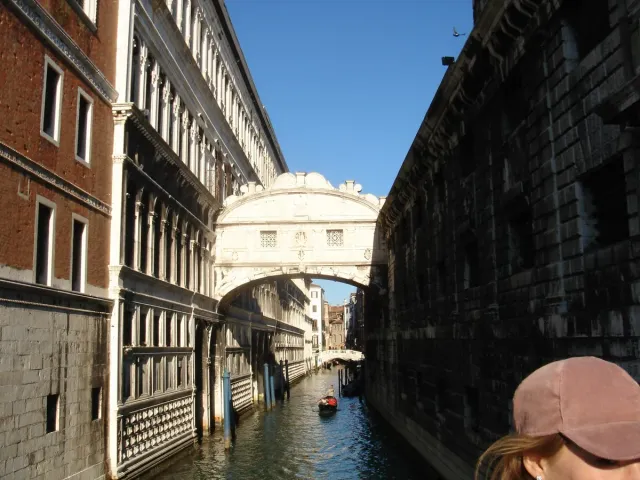 An enclosed stone bridge with barred windows spanning a canal between buildings