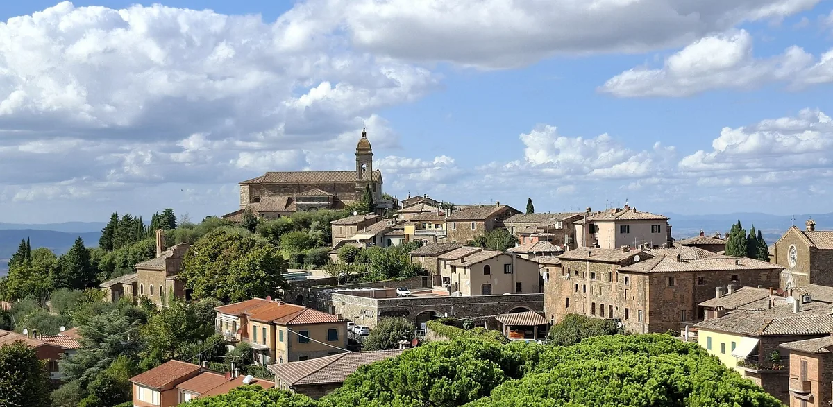 A hilltop town of stone houses and a bell tower, surrounded by greenery