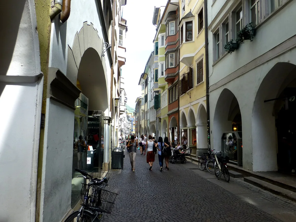 A narrow street with covered arcades on both sides and pastel coloured facades