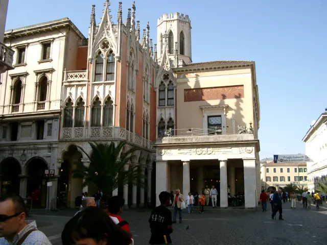 A neoclassical cafe building with columns and arches on a city square