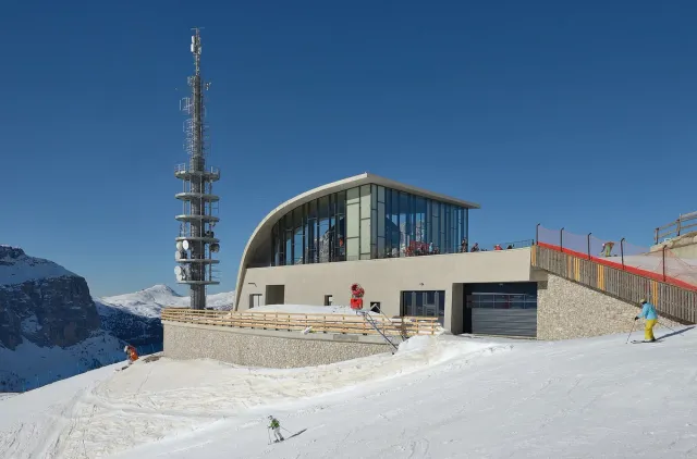 A modern cable car station on a snowy ridge with ski runs