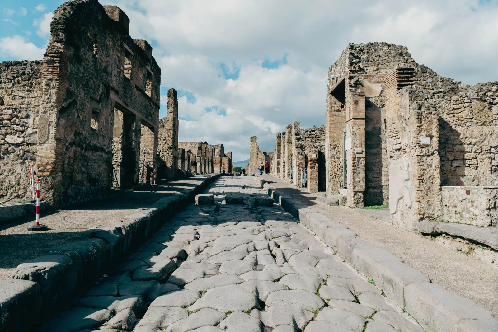 A paved street between ruined stone buildings at Pompeii, Italy