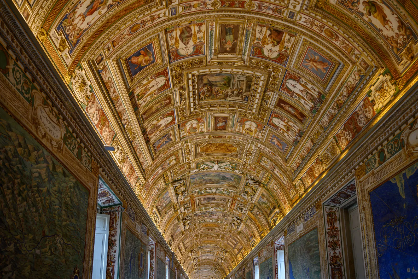 A long decorated gallery in the Vatican Museums filled with visitors in Rome, Italy